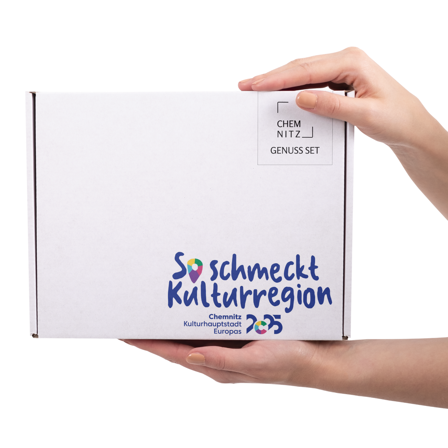 Karton (weiß) vom Genuss Set in der Edition 'So schmeckt Kulturregion'. Der Karton wird von zwei Händen gehalten.
