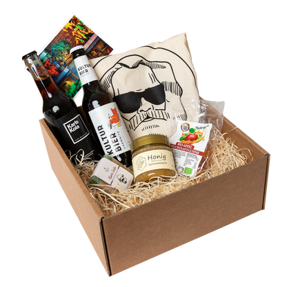 Genuss Set Chemnitz Basis mit Baumwolltasche mit Karlskopf-Logo, Karls Seife, Bio-Fruchtsaftgummi, Honig,  Karls Kola Flasche, Kulturbier Flasche in braunem Karton.